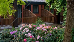 A garden with a wooden fence, a pond, and pink flowers.