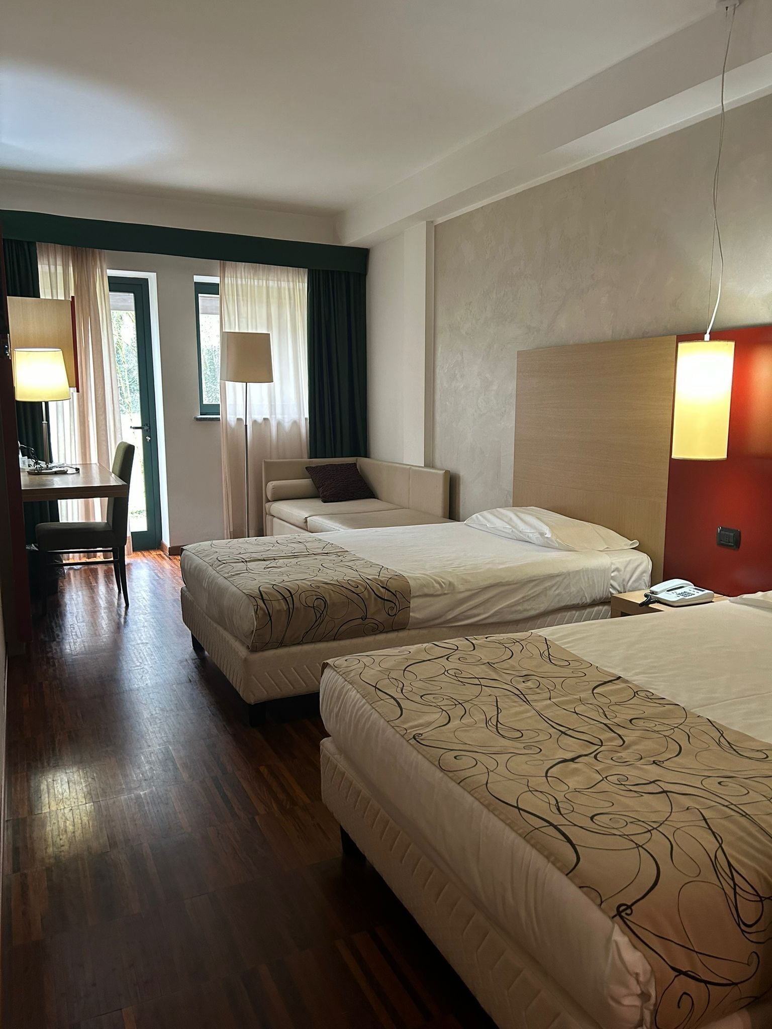 A hotel room with two beds, a desk, and a chair.