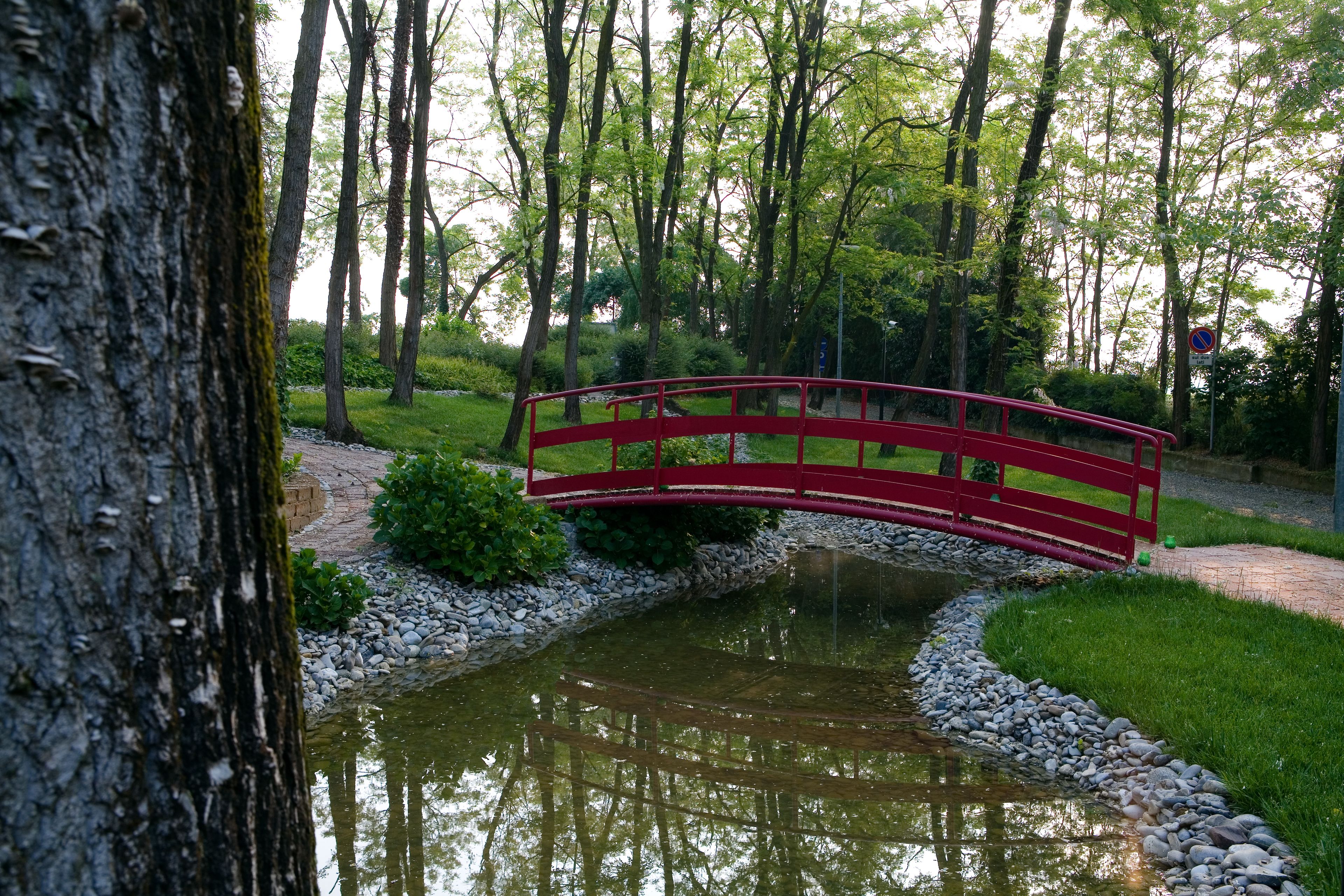 Un puente rojo sobre un estanque en un área boscosa.
