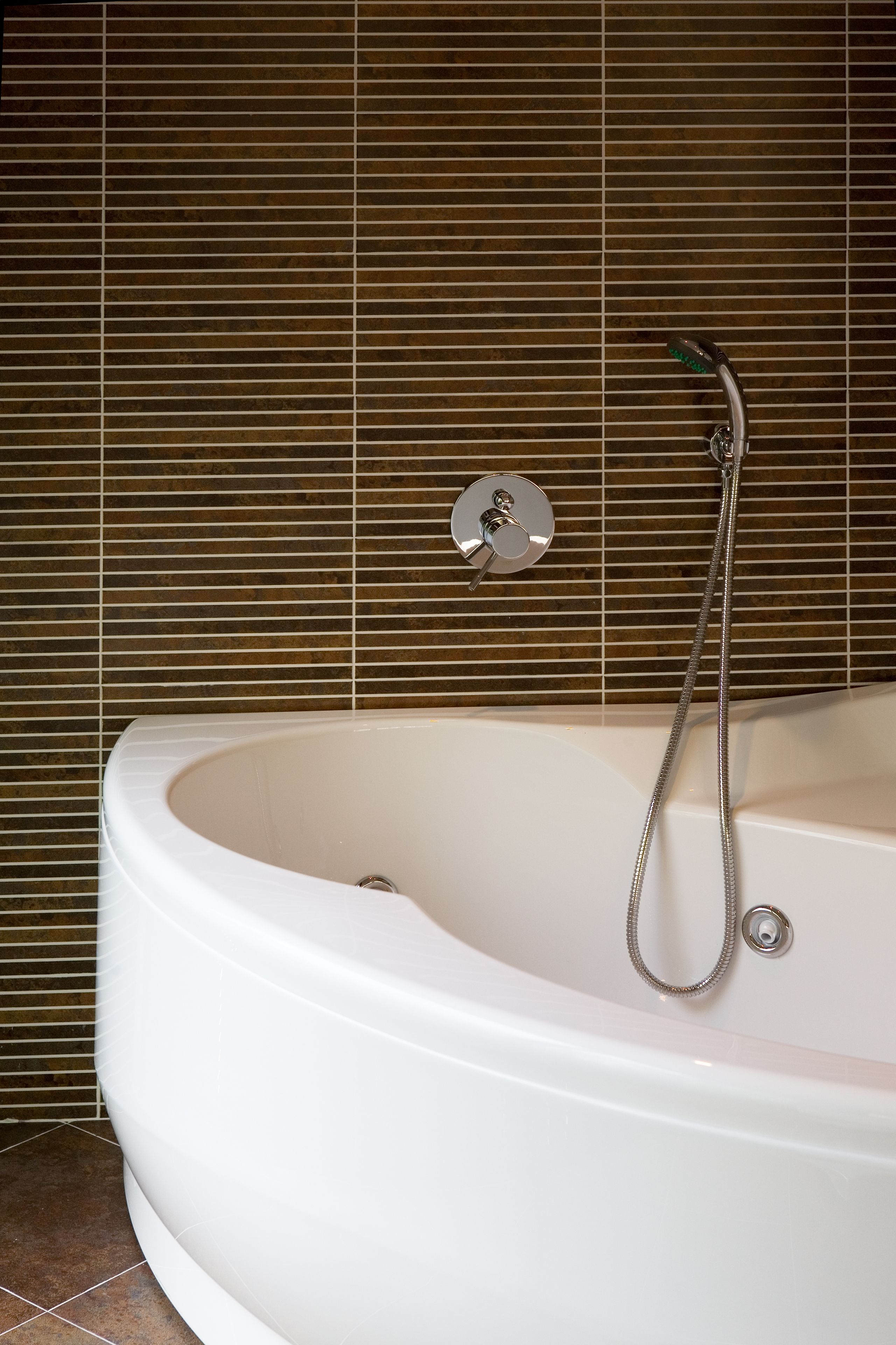 Un baño moderno con una bañera independiente, un cabezal de ducha de mano y un grifo empotrado.