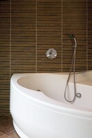 Un baño moderno con una bañera independiente, un cabezal de ducha de mano y un grifo empotrado.