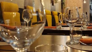 A dining area with tables set for two, featuring clear glassware and yellow cushioned seating.