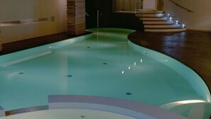 A swimming pool with a unique design, including a curved edge and a central feature resembling a small island.