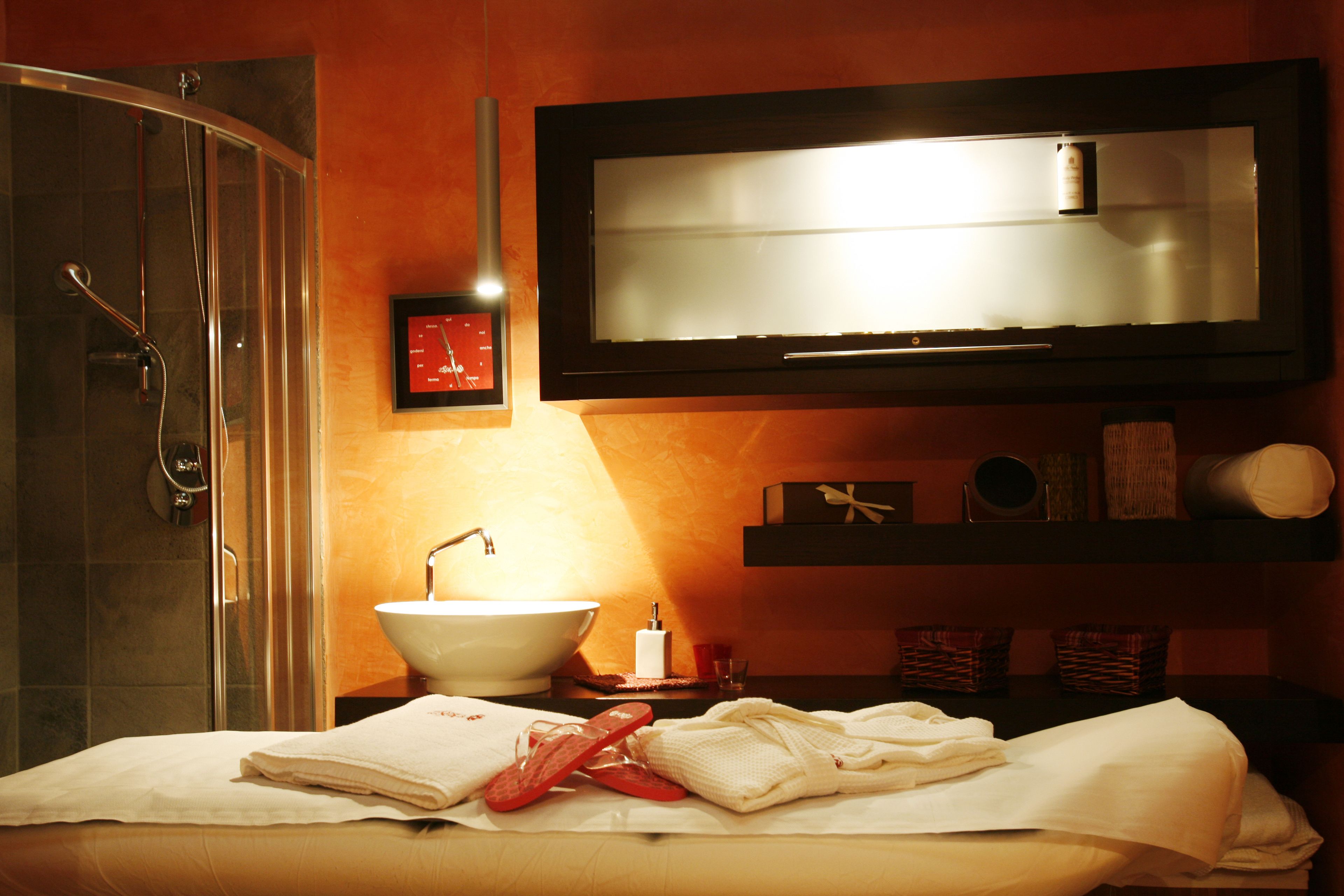 Une salle de bain avec une douche à parois de verre, un lavabo avec un miroir au-dessus et un porte-serviettes avec des serviettes.