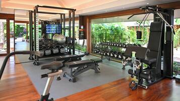 A gym with weightlifting equipment, cardio machines, and dumbbells.