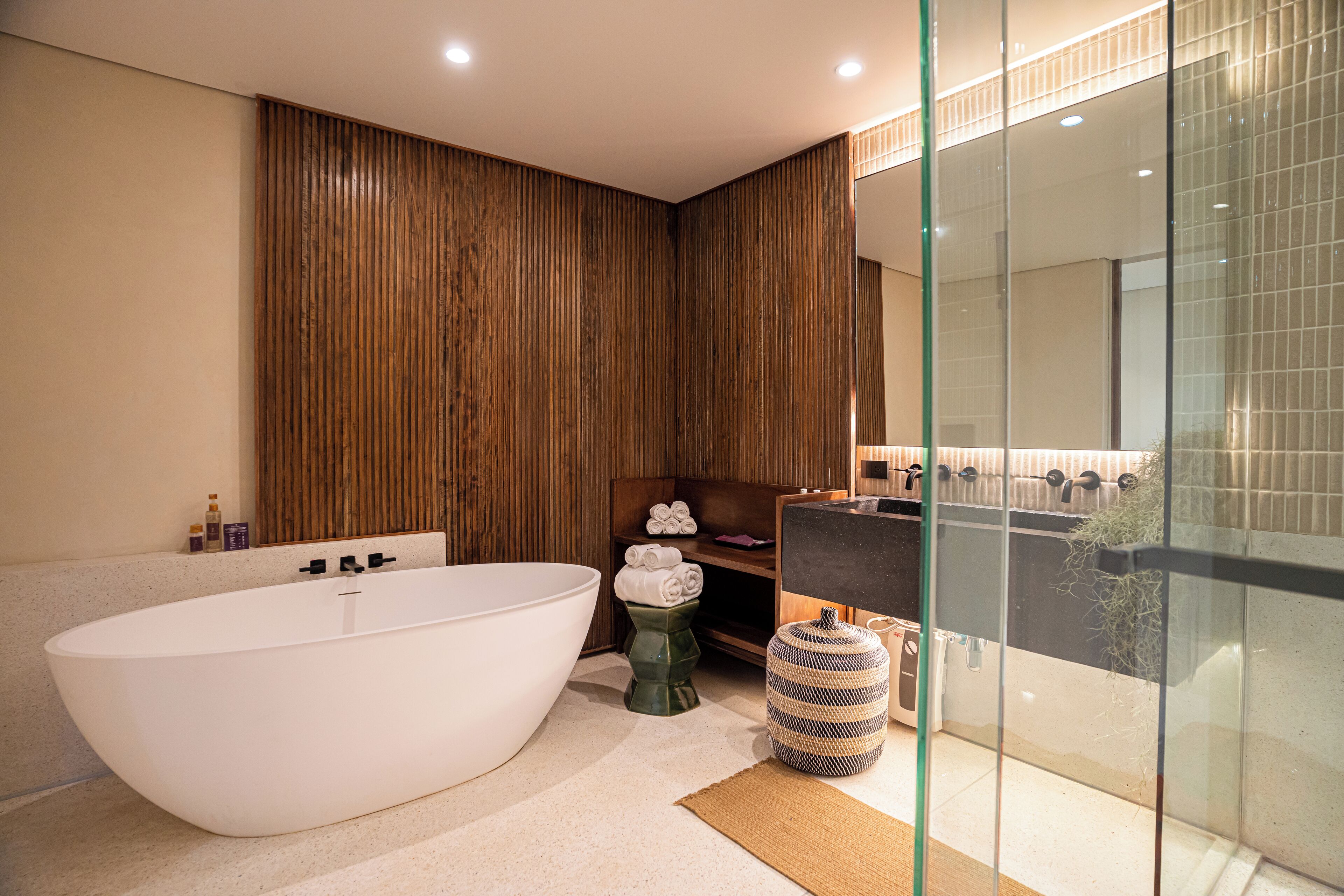 Une salle de bain moderne avec une baignoire sur pieds, un mur recouvert de panneaux en bois et une cabine de douche en verre.
