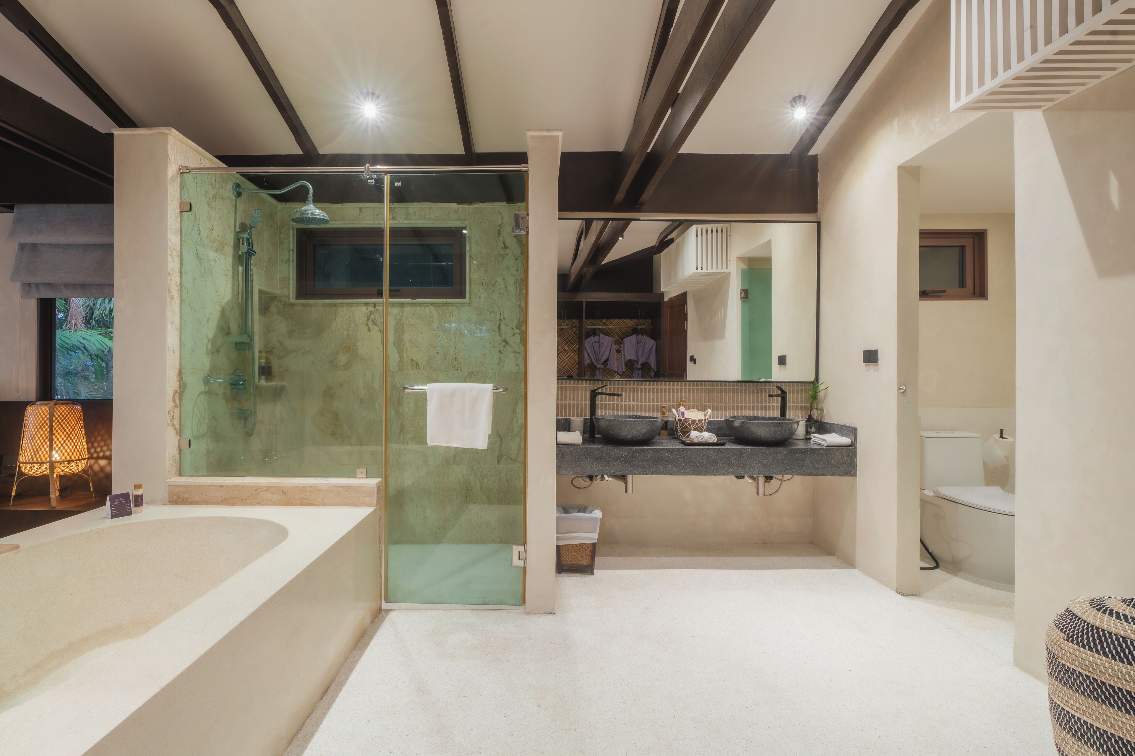 Un baño moderno con ducha de vidrio, una bañera grande y un tocador con lavamanos y espejo.