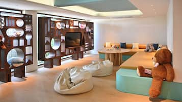 A modern interior with a sofa, bean bags, and a teddy bear.