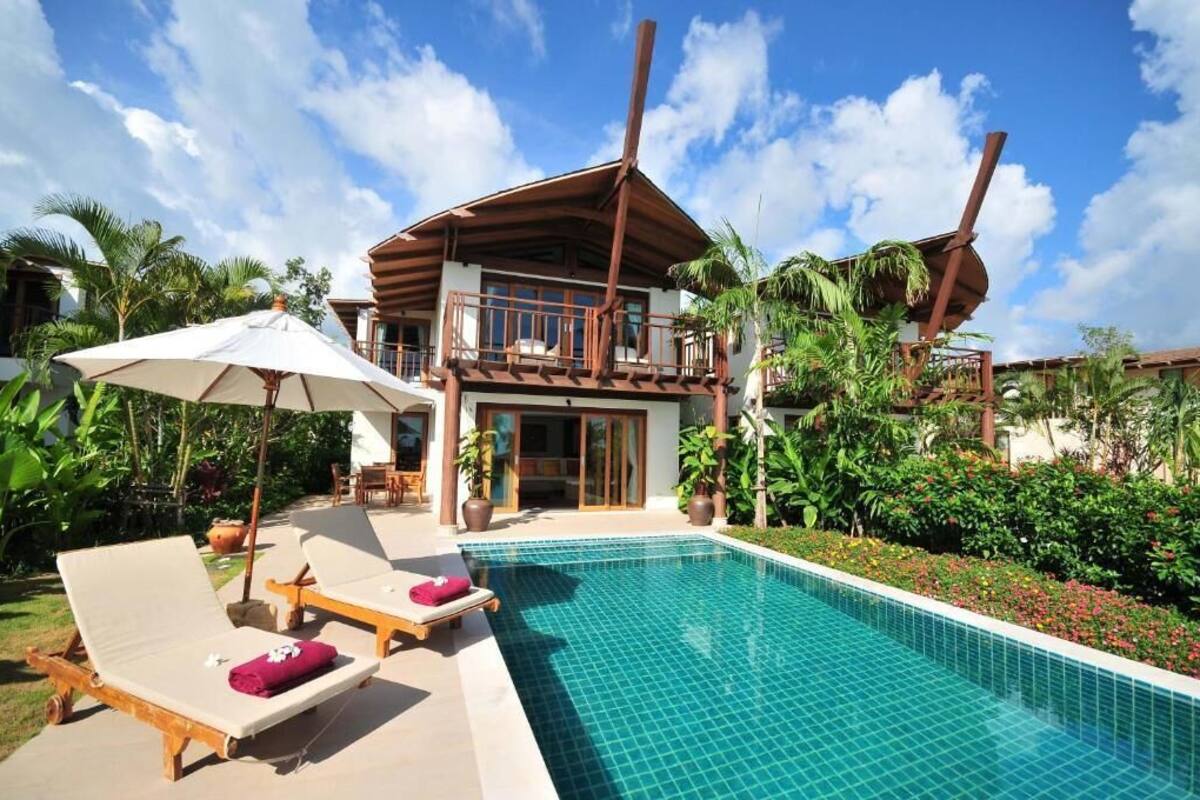 A resort with a pool, lounge chairs, and a two-story building with a balcony.