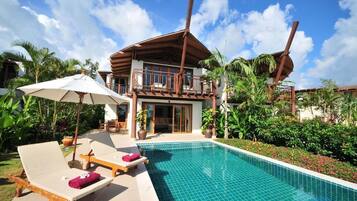 A resort with a pool, lounge chairs, and a two-story building with a balcony.