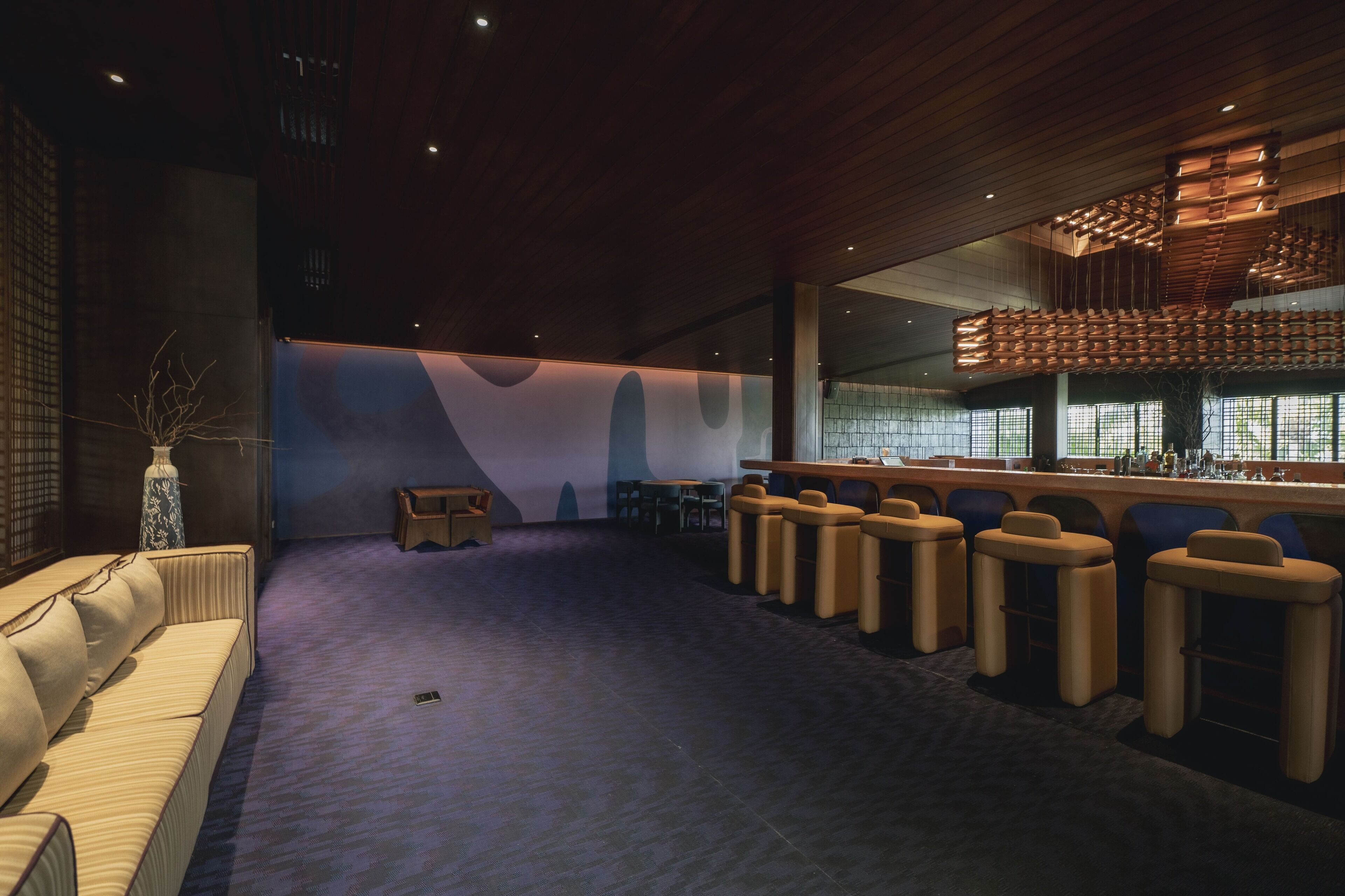 A modern lounge area with a sofa, bar stools, and a bar counter.