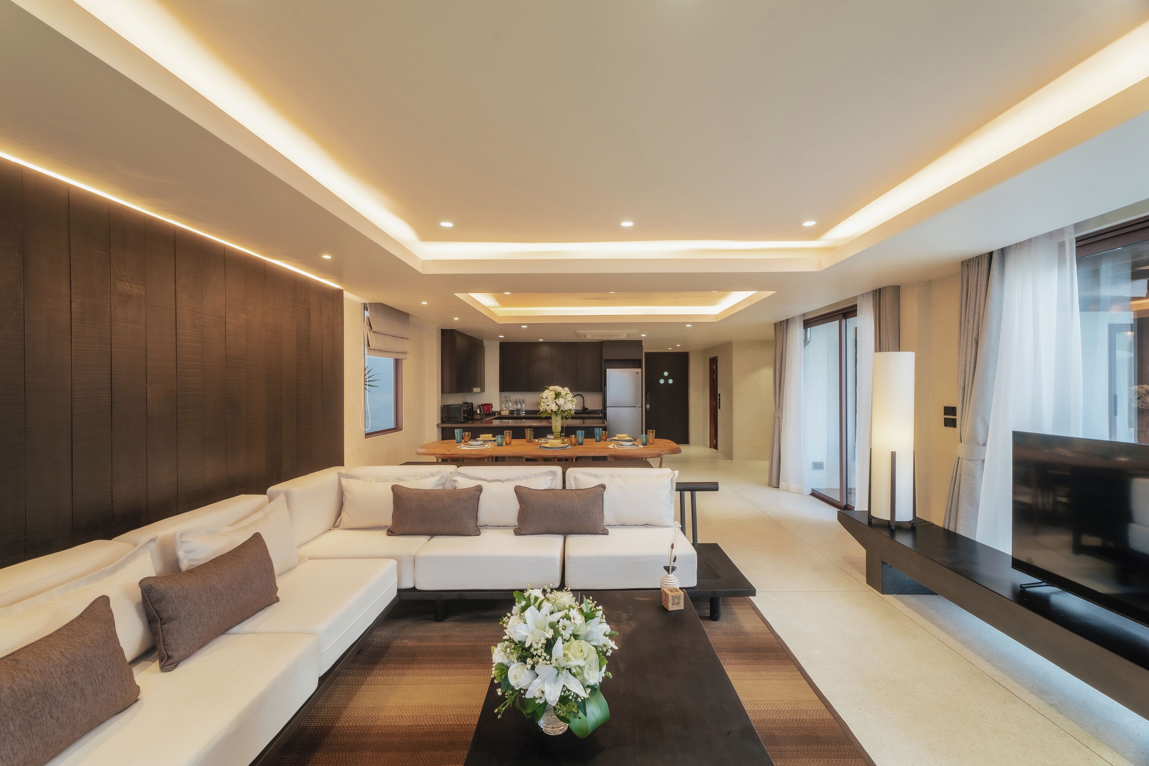 A modern living room with a sofa, coffee table, and a kitchen in the background.