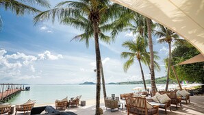 A deck with wicker furniture, a view of the sea, and palm trees. - Barcelo Coconut Island Phuket (Maprao Island)