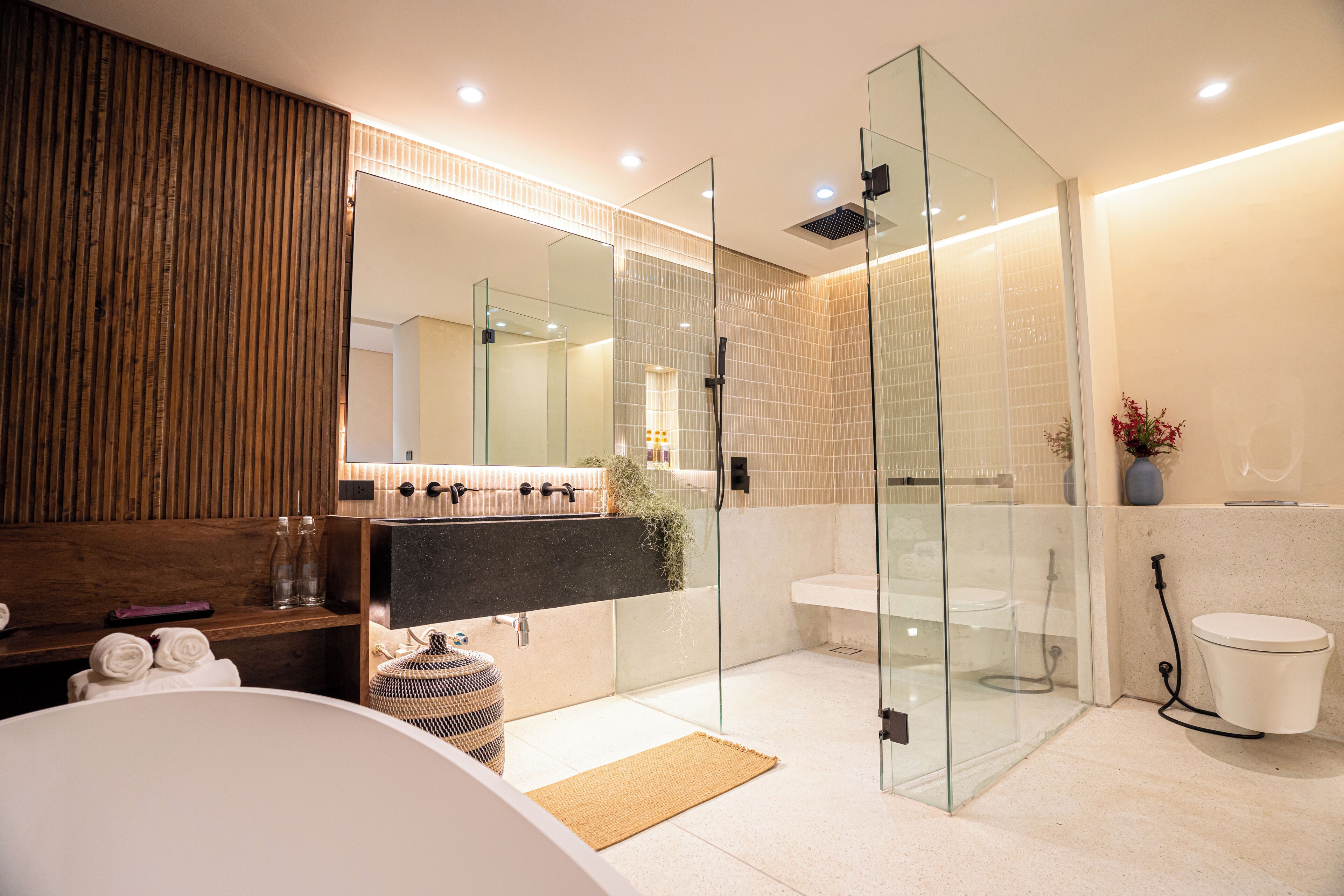A modern bathroom with a glass-enclosed shower, a large mirror, and a wooden vanity.