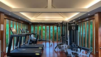 Ein Fitnessstudio mit Laufbändern, Kraftgeräten und einem großen Fenster mit Blick auf Grünflächen.