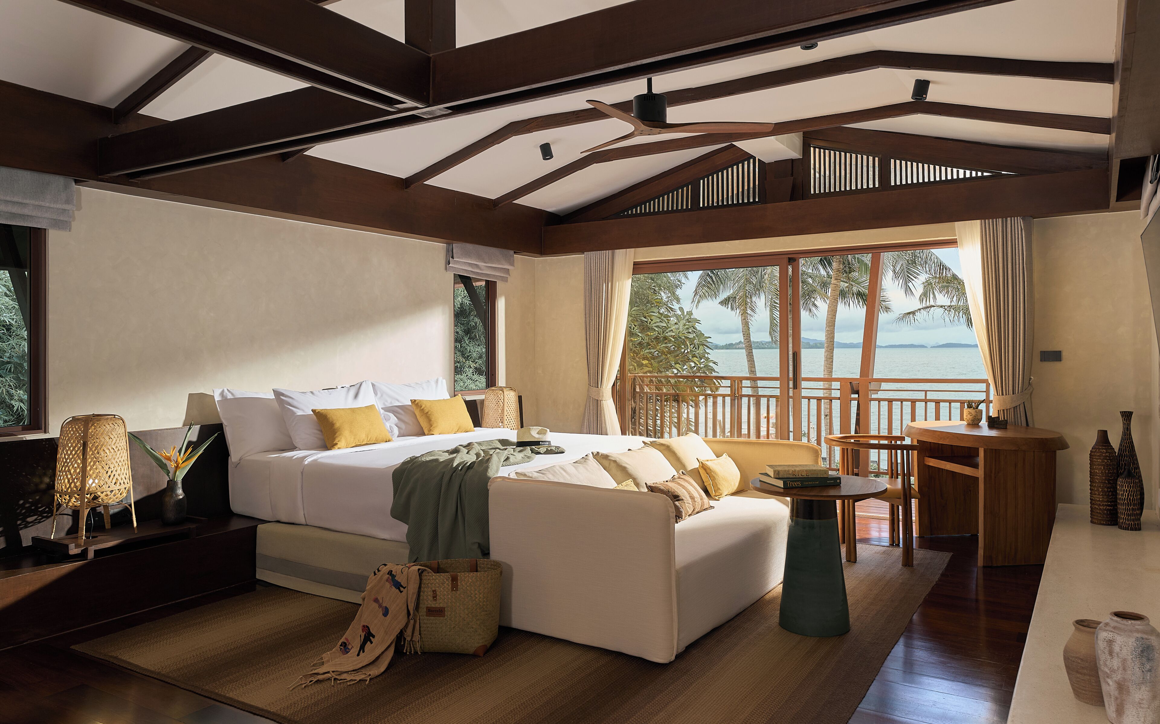Een ruime slaapkamer met een groot bed, een zithoek met een tafeltje en uitzicht op zee.