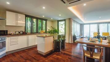 Une cuisine moderne avec des meubles blancs, un îlot central et un coin repas comprenant une table et des chaises en bois.