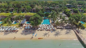 A resort with multiple swimming pools, a beach, and a mountainous backdrop. - Barcelo Coconut Island Phuket (Maprao Island)