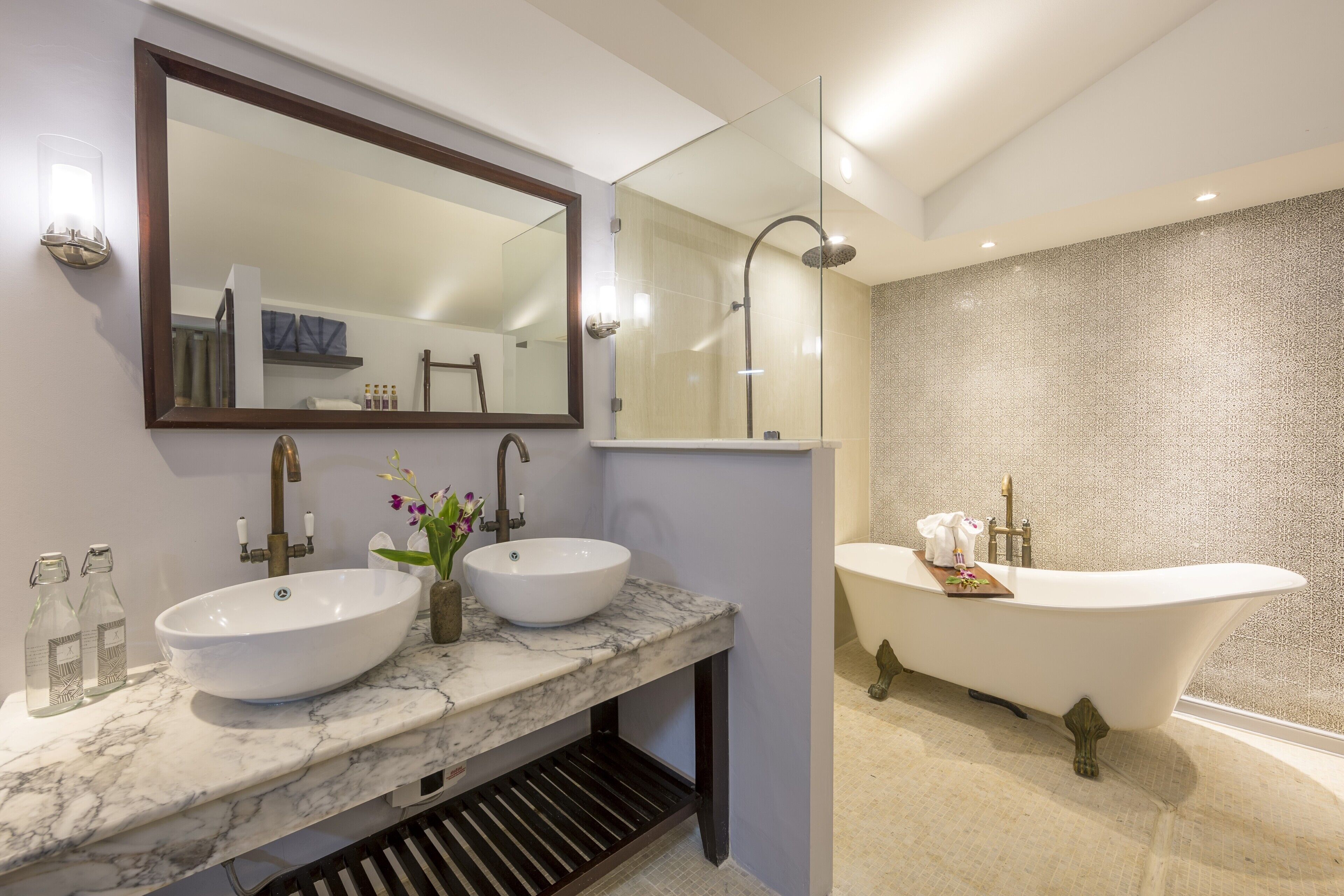 A modern bathroom with two sinks, a large mirror, and a freestanding bathtub.
