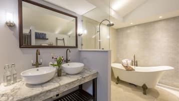 A modern bathroom with two sinks, a large mirror, and a freestanding bathtub.
