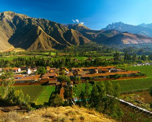 Un pueblo rural con casas tradicionales, campos en terrazas y montañas al fondo.