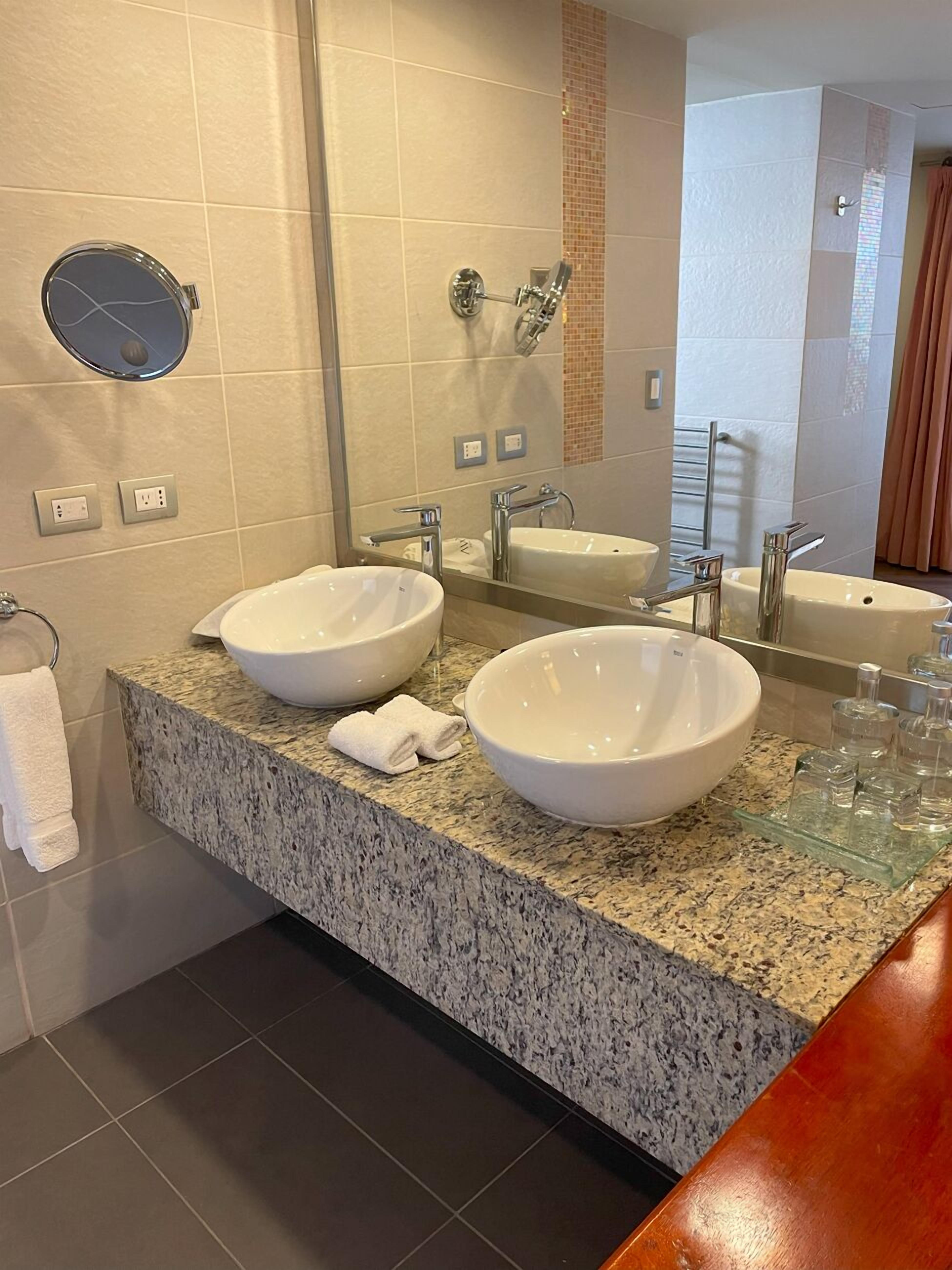 Een badkamer met twee wastafels, een grote spiegel en een granieten aanrechtblad.