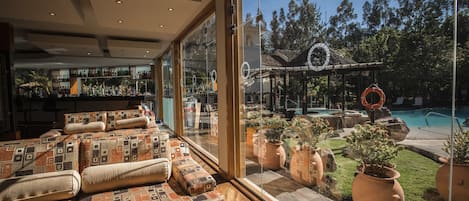 Un interior moderno con un amplio ventanal que da a una piscina y jardín.