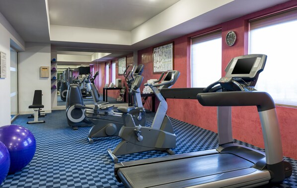 Un gimnasio con cintas de correr, elípticas y pelotas de ejercicio.