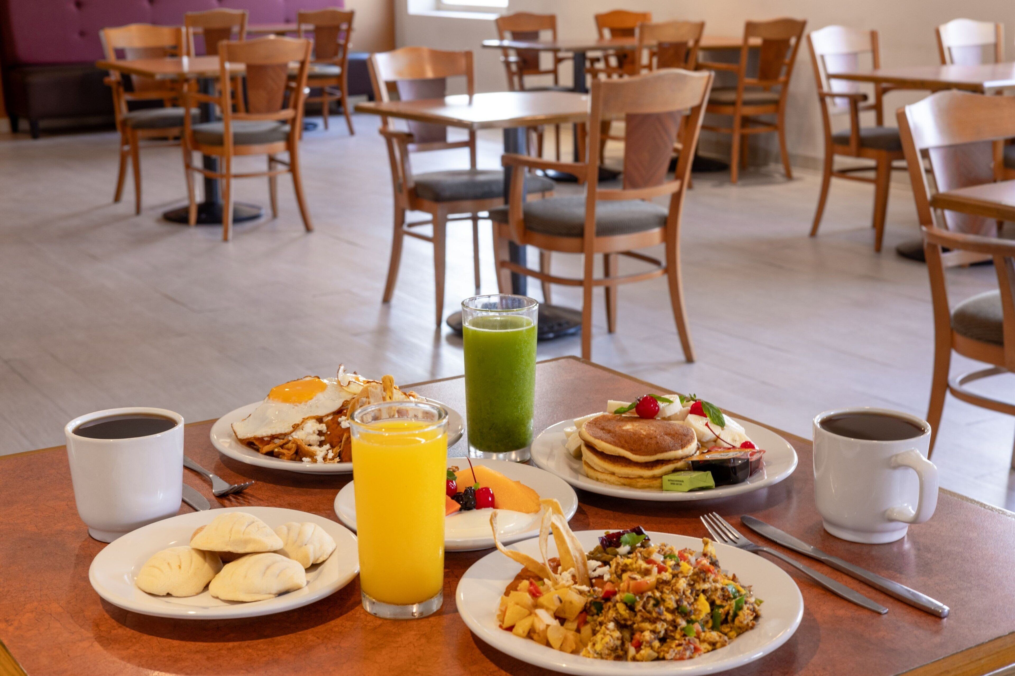 Un bufé de desayuno con diversos platos, como huevos, panqueques y fruta.