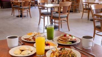 Un bufé de desayuno con diversos platos, como huevos, panqueques y fruta.