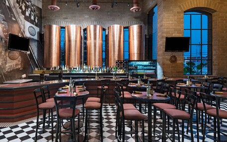 A bar area with copper columns, checkered flooring, and multiple seating arrangements.