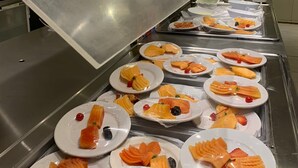 Un bufé con diversos platos, entre ellos salmón y frutas, presentados en fuentes.
