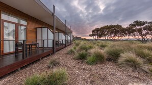 Un bâtiment moderne doté d’une terrasse en bois et d’un espace extérieur aménagé pour s’asseoir.