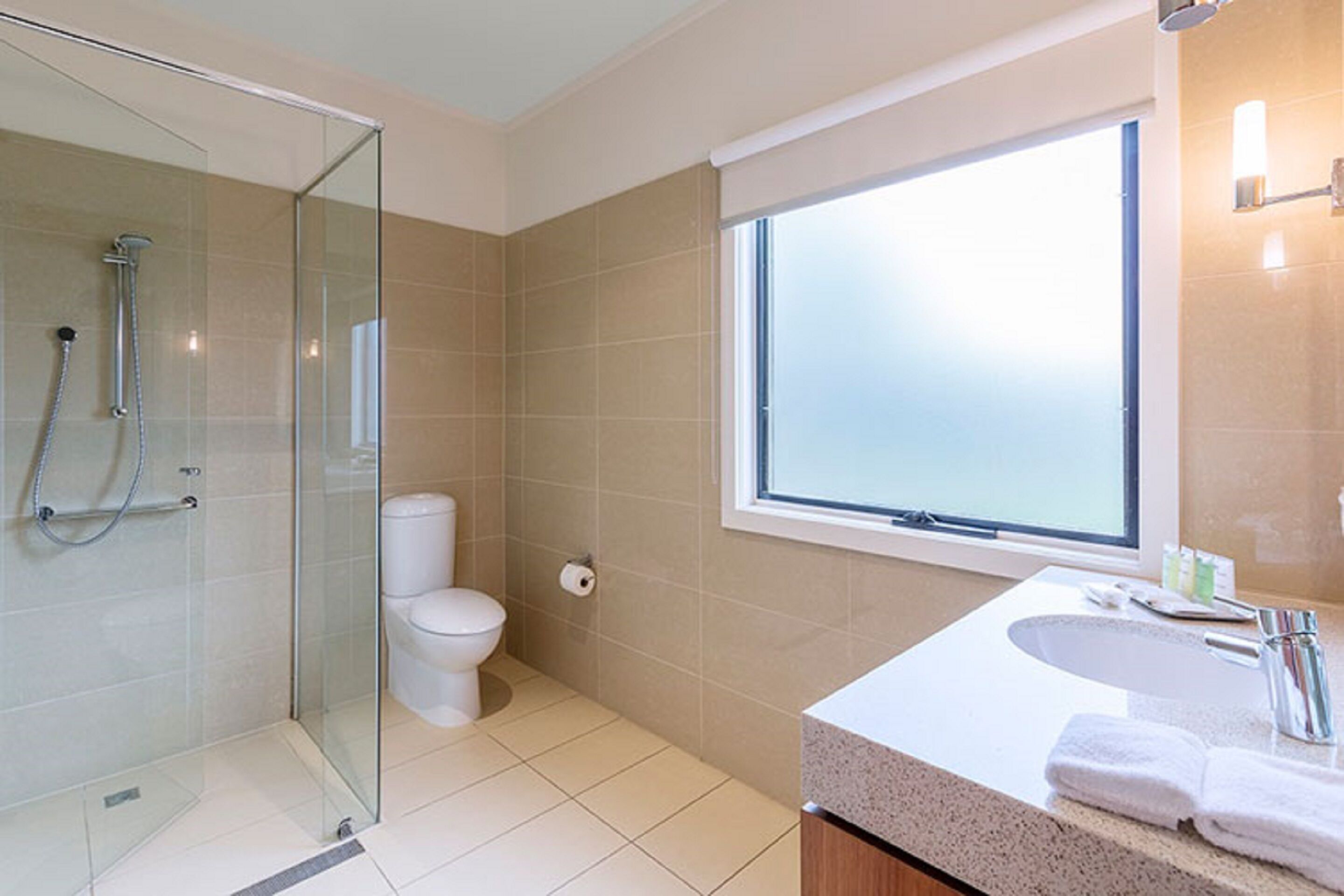 A modern bathroom with a glass-enclosed shower, a toilet, and a sink with a countertop.