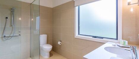 A modern bathroom with a glass-enclosed shower, a toilet, and a sink with a countertop.