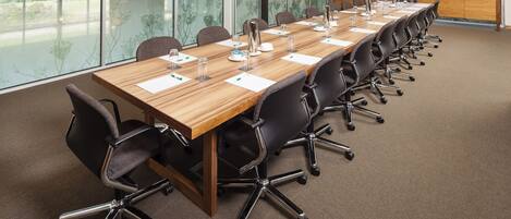 A conference room with a long table, chairs, and a view of the outdoors.