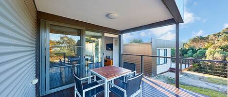 A balcony with a table and chairs, a sliding glass door, and a view of the surrounding landscape.