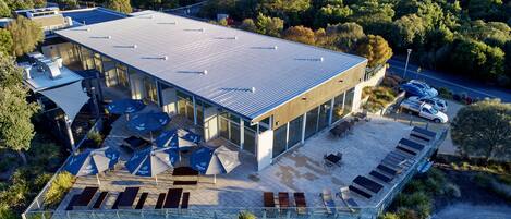 A modern building with a flat roof, large windows, and outdoor seating.