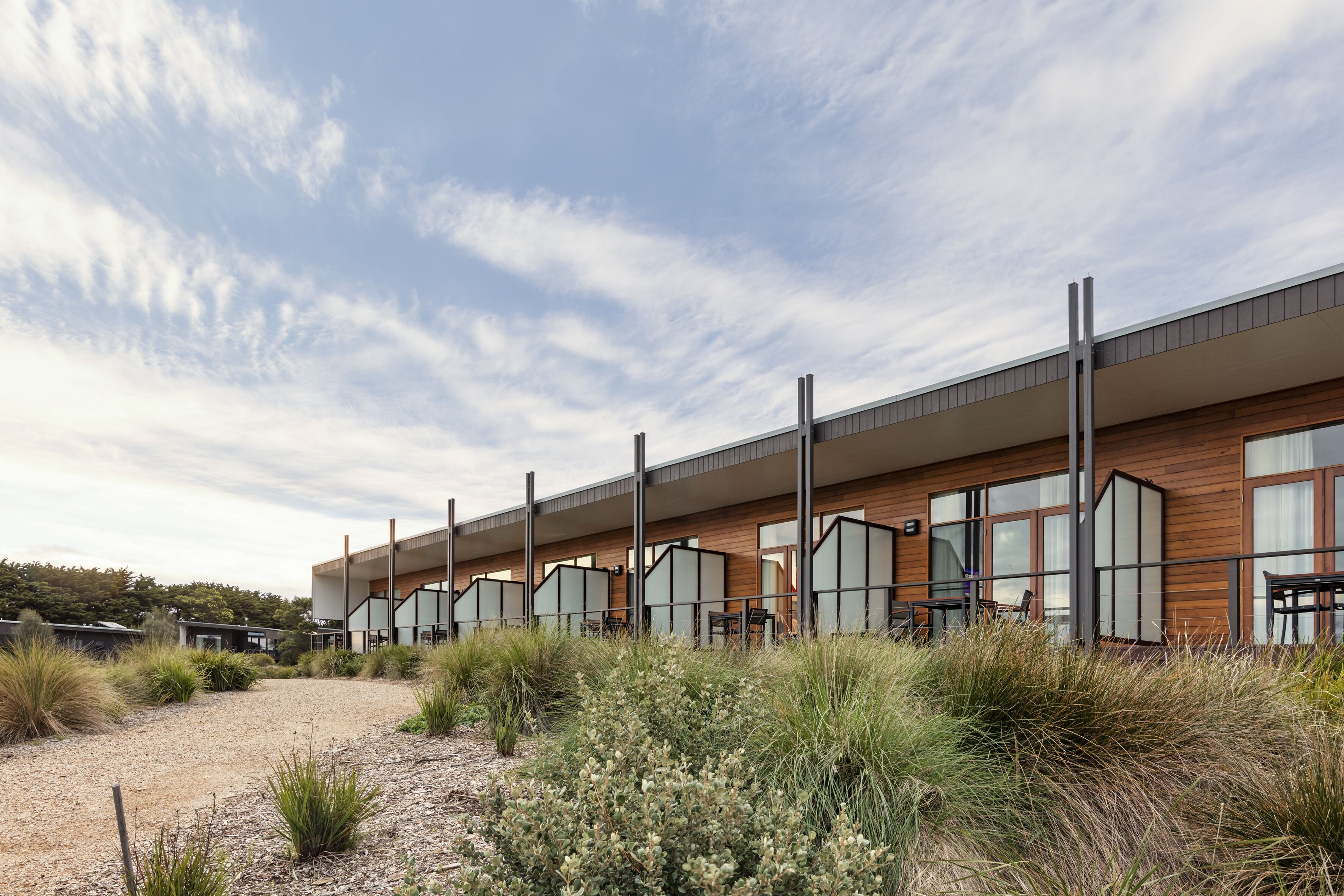 A modern building with large windows and a flat roof, surrounded by natural vegetation.