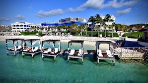 A beachfront resort with overwater bungalows, a pool, and a clear blue sky.