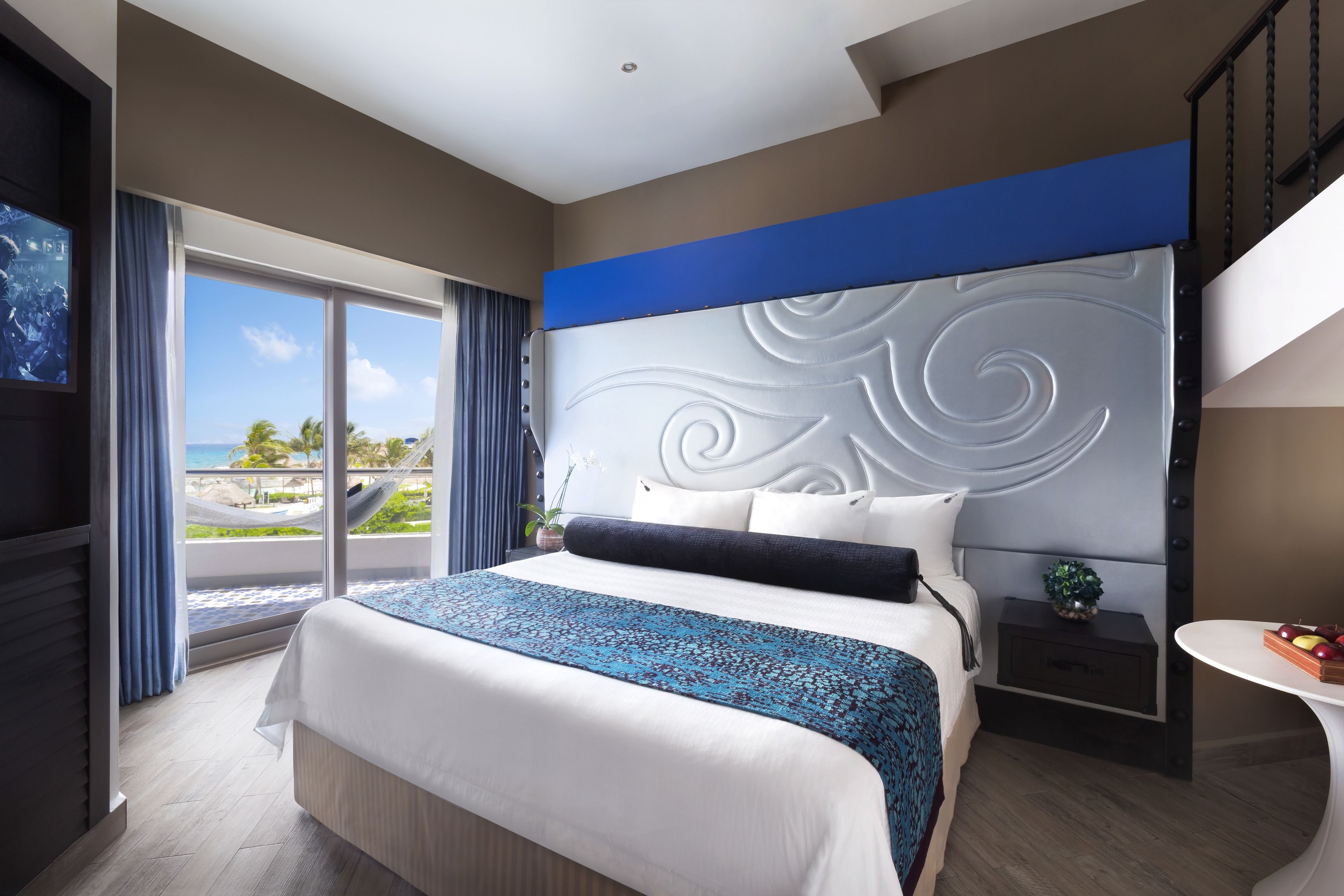 Habitación de hotel moderna con una cama grande, vistas a la playa y un balcón.
