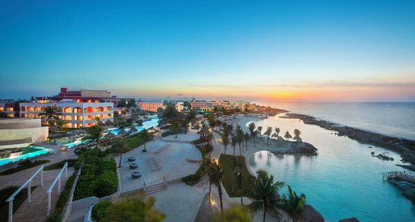 Un resort con varias edificaciones, una piscina y una zona de playa.