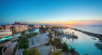 Un resort con varias edificaciones, una piscina y una zona de playa.
