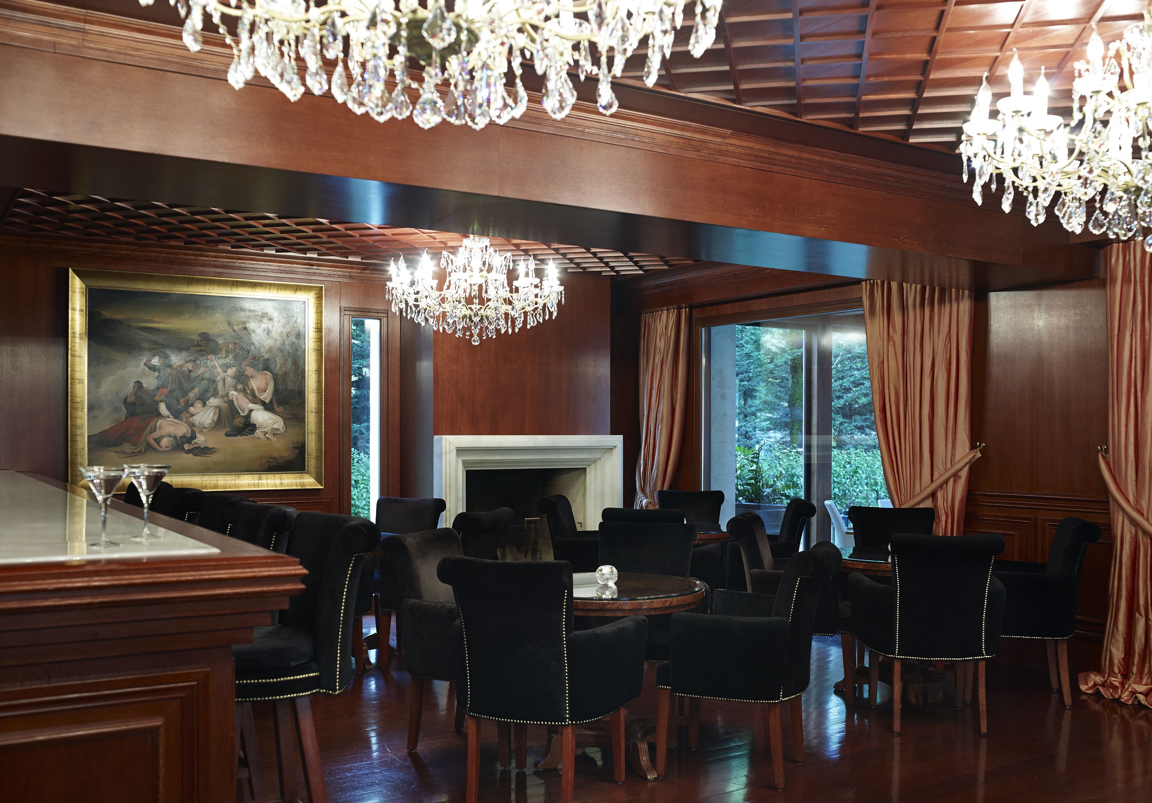 A formal dining room with a large painting, chandeliers, and a fireplace.