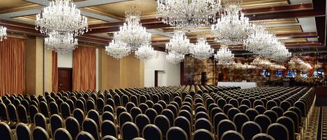 A large conference room with rows of chairs and multiple chandeliers.