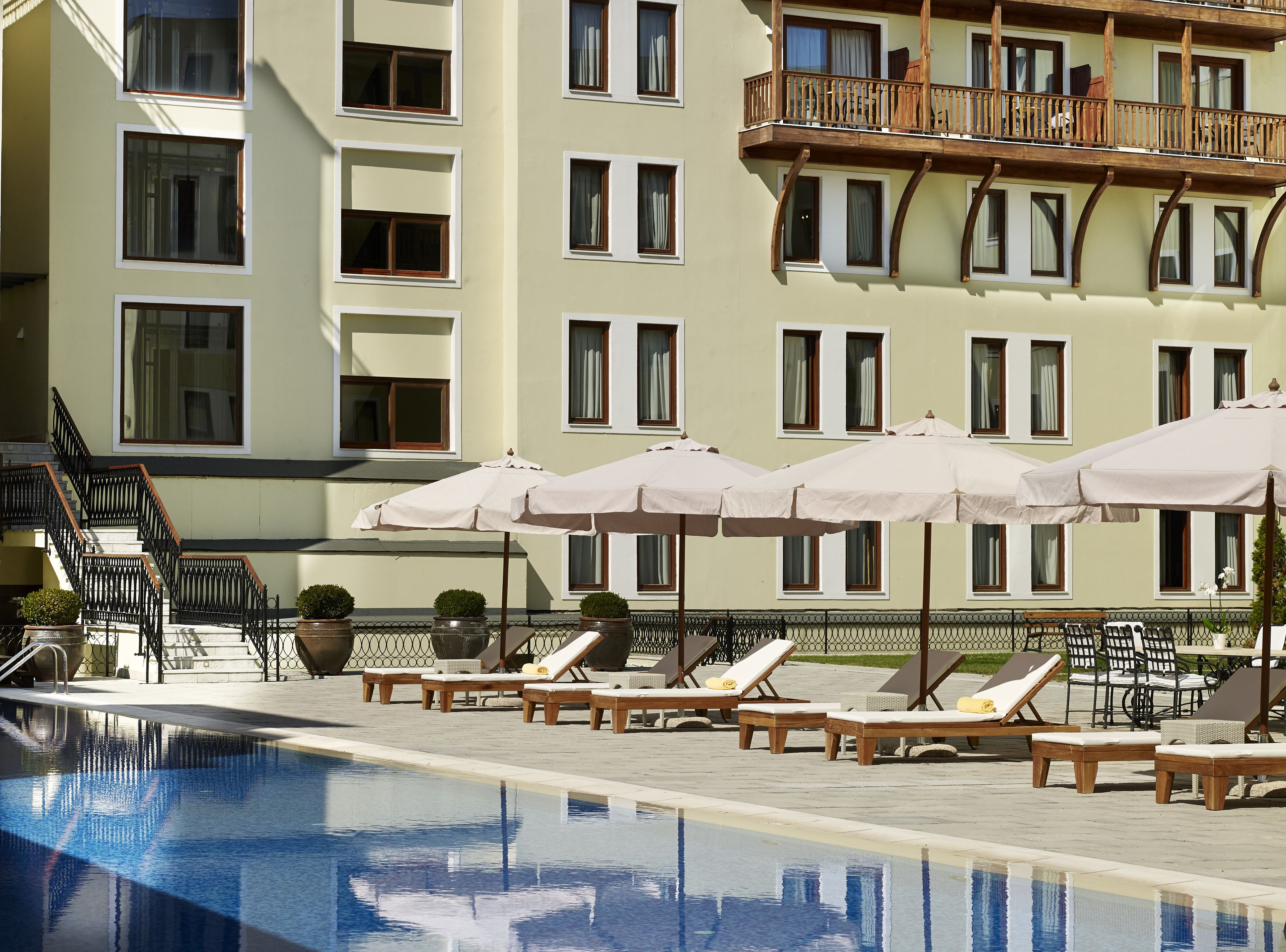 Ett hotell med en swimmingpool, solstolar och parasoller.