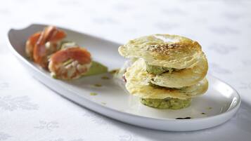 A white plate with a stack of pancakes and a piece of salmon on a white tablecloth.