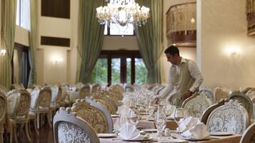 Un comedor formal con sillas ornamentadas, una mesa larga dispuesta para una comida y una araña.