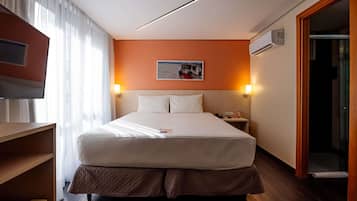 Una habitación de hotel con una cama, mesitas de noche, un televisor y un cuadro en la pared.