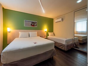 A hotel room with a large bed, a smaller bed, a nightstand, an air conditioning unit, a wall-mounted picture, and a mirror. - ibis Styles Belém Batista Campos (Belém)